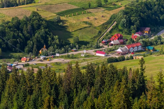 A resort village with large buildings, small houses and a wooden temple at the foot of the high green mountains