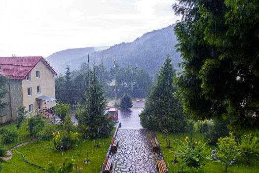 Large drops of rain fall on the house with a small park around it