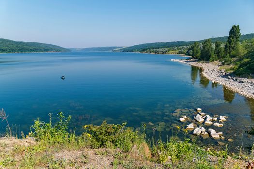 Crystal clear mountain lake. At the bottom are visible stones. A place for rest and fishing