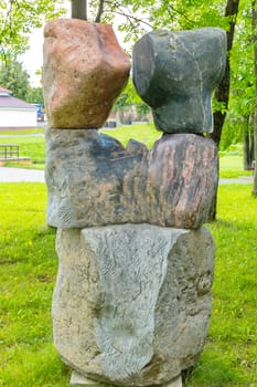 Stone sculpture with huge boulders against the background of a smoothly cut green lawn