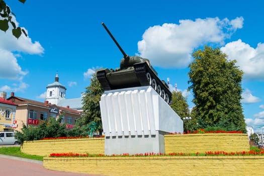 The installed tank on a monument raises its muzzle in a blue sky