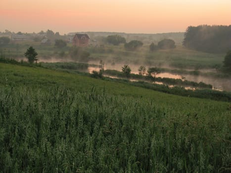 fog rising up the lake in the valley at dawn before sunrise, among the fields