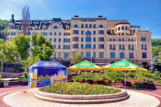 the area with a flowerbed and umbrellas above the tables on the background of a beautiful facade of the house