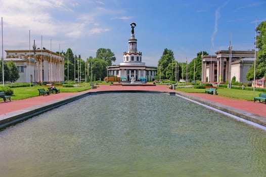 a large pool in the city on the background of a monument and installed benches to rest around it