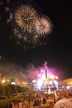 city evening with people celebrating the holiday under the flashes of a colorful salute