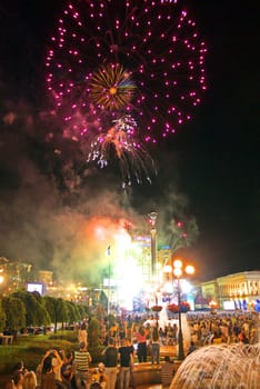 bright flashes of beautiful fireworks in the city against the background of a large number of people