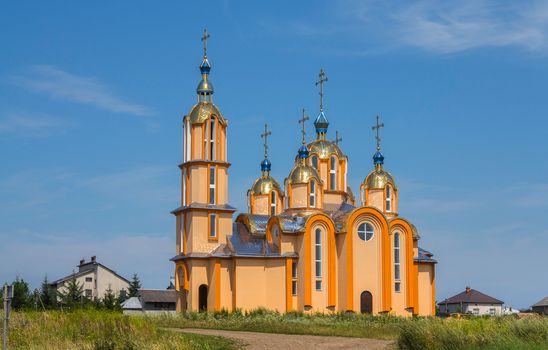 A large orange church with a huge number of golden domes against the blue sky