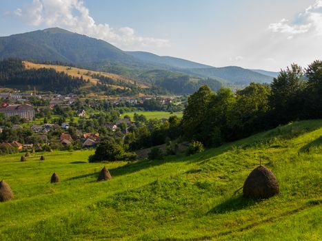 downhill from the mountain to the city overgrown with grass. Sush hay is packed in a pile