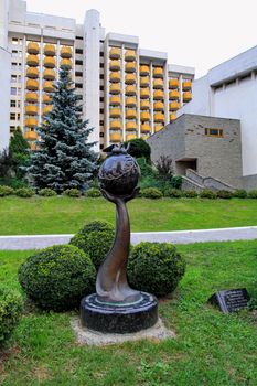 modern monument is a hand that holds the planet earth in the courtyard near a new home in the city