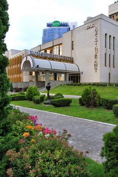 A modern business center with well-groomed adjacent territory on the background of a high glass building