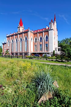 Flower bed with decorative flowers and shrubs on the background of a temple with a red acute-angled roof