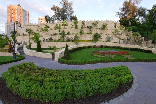 green lawns and designer flower beds in the park against the background of a high-rise building