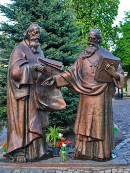 Sculpture of two saints of old age people with a cross on their necks and a book in the hands of one and sheets of manuscripts from the other.