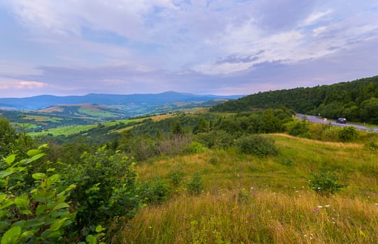 winding trail on a mountain valley on the background of distant hills on which a straight blue car