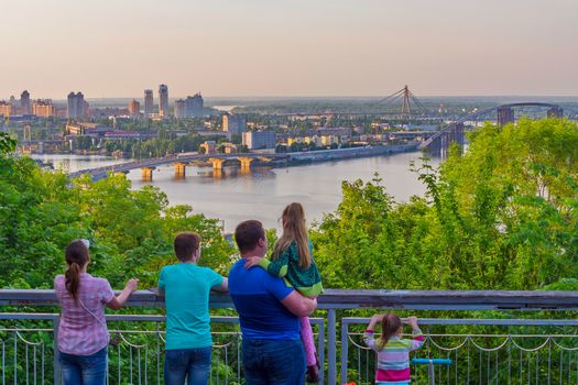The family looks at the panorama of the city with three bridges over the Dnieper among the lush greenery. Kiev. Ukraine