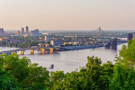 A bridge of colossal size going through a wide river. A beautiful city landscape
