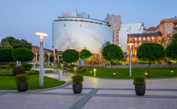 High modern building of the hotel with transparent windows on the background of the green park zone