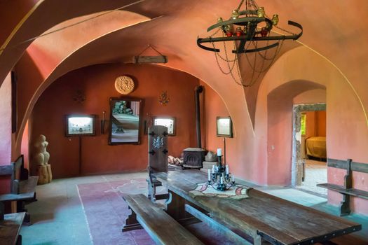 Museum exposition of a medieval room with a long dining table, high chairs and a decorative chandelier above them