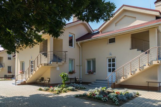 terrace near tidy, clean cottages with flowerbeds in the yard. At the stairs, a chairs for rest