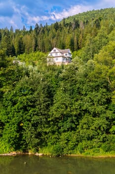A cozy three-storey villa is located on the slope of a high green mountain near a beautiful lake