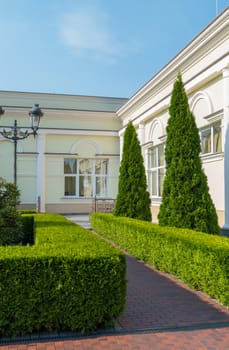white private residence with a beautiful well-groomed territory, on which grow pyramidal thai, neat trimmed shrubs, lantern. against the blue cloudless sky