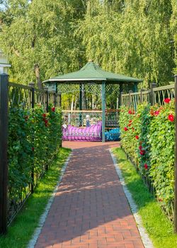 alley leading to the gazebo with a fence lined with red roses