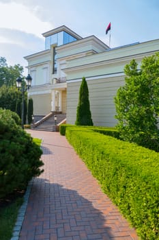 A paved stone path to the building next to a well-groomed lawn