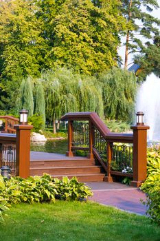 Stairs to a wooden bridge with railing through the river in the city park near the fountain of the wreath of willow