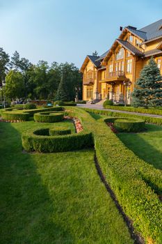 Decoratively trimmed lawn at the entrance to the chic large wooden house