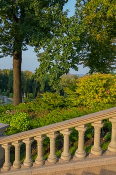 Stairs with handrails in antique style in the park on the background of rich green oak leaves