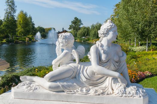 a statue of white marble Aphrodite with an angel on the river bank