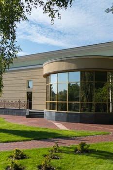 The building has a semi-circular foyer with mirrored windows and a lawn with green grass in front of it