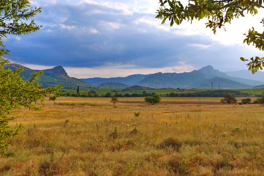 A beautiful landscape of plain with a withered grass with green mountain slopes on the horizon line.