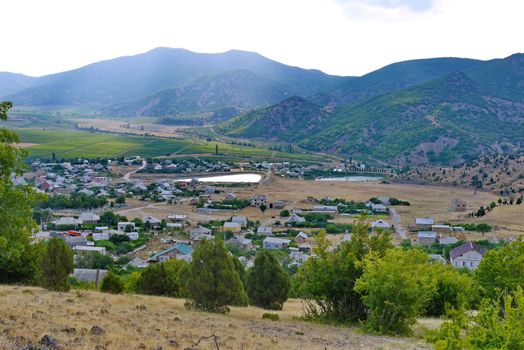 industrial unpopular small town in the valley of mountains with small ponds and green fields