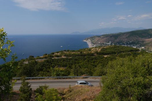 A picturesque view of a pretty resort village amidst the wide green mountains and the blue sea