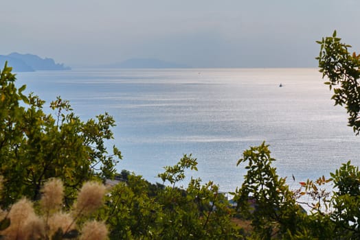 The glitter of the surface of sea water in the bay on the background of the distant foggy mountains