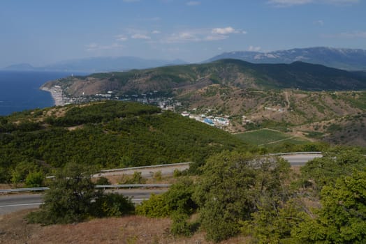amazing scenery seen far off the sea and houses on the shore lying in the valley between the green forest and the mountain slopes