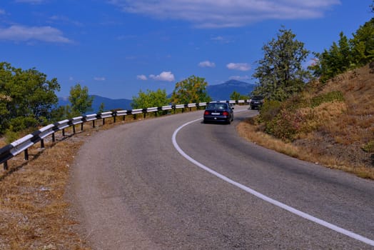 The mountain road turns right to the background of a cloudy sky in clear weather. place of rest, tourism, picnic