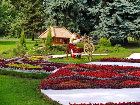 Silhouette of a girl in traditional clothes made entirely of decorative flowers on the background of the old Ukrainian hut