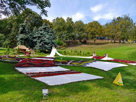 decorative flowerbeds in the form of embroidered towels with Ukrainian girls in wreaths and backgrounds of green grass