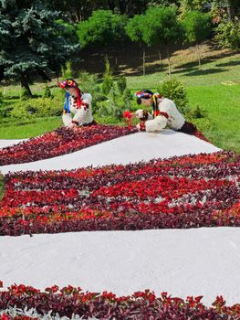 Girls in ethnic Ukrainian clothes from flowers near flower beds on a white background in a pack zone.