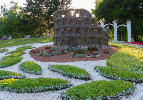 Beautiful flowerbed and sculpture of a partially destroyed Colosseum on it