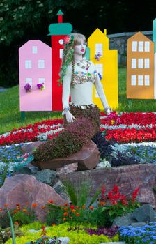 on the flowerbed a statue of flowers from the mermaid on the background of bright colored houses
