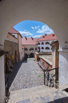 Large white arch with steps leading to the square with benches, souvenirs and beautiful architectural houses