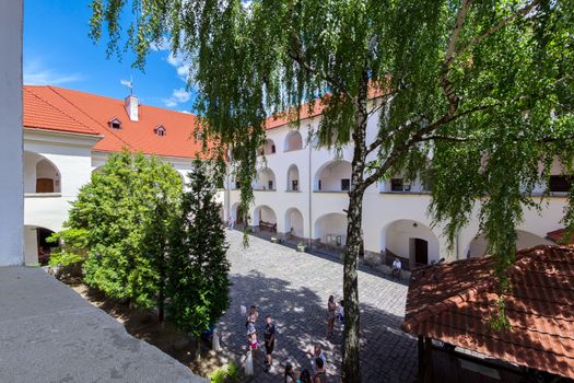 Tourists on the central square of the ancient Ukrainian castle with a red roof