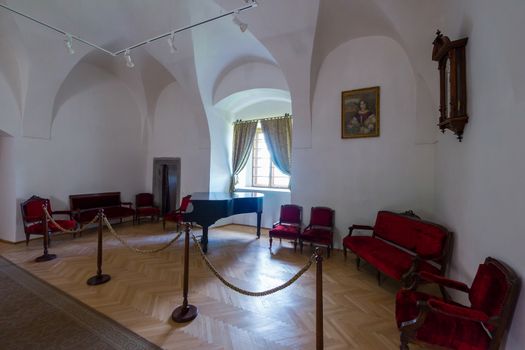 Corner in the museum with furniture made of velvet plating and black old piano