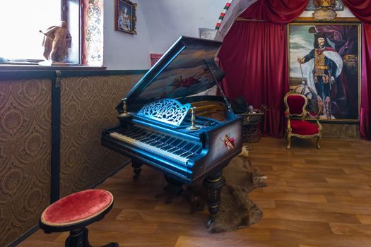 Ancient black piano, chairs, paintings and other exhibits of the museum exhibition