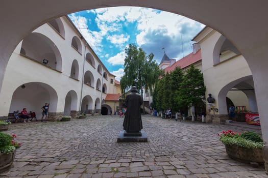 A beautiful monument in the middle of an ancient square with beautiful flower beds and a view of the castle tower