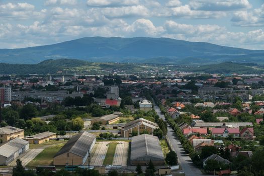 Beautiful view of the city at the foot of the green misty mountains against a blue cloudy sky