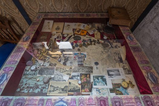 A glass rack with antique clocks, photographs, coins and awards. On it is the same old book